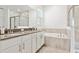 Well-lit bathroom featuring dual sinks, a soaking tub, a glass shower, and neutral tile at 1720 Sourwood Dr, Ocoee, FL 34761