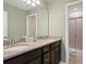 Bathroom featuring double sinks with granite countertops, dark wood cabinets, and a glass-enclosed shower at 2221 Lelani Cir, Davenport, FL 33897