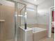Bright bathroom showcasing a glass shower, soaking tub, and a view towards the bedroom at 2221 Lelani Cir, Davenport, FL 33897