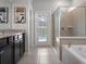 Elegant bathroom featuring black cabinetry, granite counters, and a glass-enclosed shower near the tub at 2221 Lelani Cir, Davenport, FL 33897