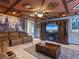 Living room with themed design, stone accent wall, wood ceiling beams, and a comfortable brown sofa at 2221 Lelani Cir, Davenport, FL 33897