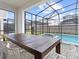 Outdoor dining area with a table, screened-in pool, and inviting spa for relaxation at 2221 Lelani Cir, Davenport, FL 33897