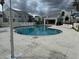Community pool with lounge chairs, surrounded by condo buildings and a cloudy sky at 2564 Woodgate Blvd # 102, Orlando, FL 32822