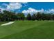 Scenic view of the pristine golf course with a lush green fairway, mature trees, and a sand trap on a sunny day at 3104 Harrison Ave # A6, Orlando, FL 32804
