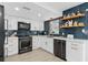 Well-lit kitchen boasting white cabinetry, a black stainless steel range, dark backsplash, and open wood shelving at 3104 Harrison Ave # A6, Orlando, FL 32804
