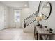 Bright foyer with neutral tile flooring, staircase with black railings, and decorative console table at 3953 Saltmarsh Loop, Sanford, FL 32773