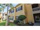 Exterior of a yellow two-story building, showcasing window shutters, a balcony, and lush landscaping at 5005 City St # 1315, Orlando, FL 32839