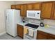 Kitchen featuring white appliances, wood cabinetry, and efficient layout with ample counter space for meal prep at 649 Gazelle Dr, Kissimmee, FL 34759
