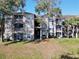 Exterior of a well-maintained condo building featuring screened balconies and manicured lawns at 7147 Yacht Basin Ave # 115, Orlando, FL 32835