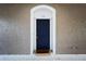 A charming front door with a blue door, white trim, and textured walls at 7147 Yacht Basin Ave # 115, Orlando, FL 32835