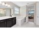 Bright bathroom with white tiled floor, a built-in tub, dark vanity with light countertop, and large mirror at 8390 Ludington Cir, Orlando, FL 32836