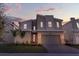 Beautiful modern two-story home featuring stone accents, a red door, a paver driveway, and manicured landscaping at sunset at 8824 Cruden Bay Ct, Davenport, FL 33896