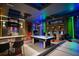 Spacious game room featuring a pool table, arcade games, bar seating, and vibrant lighting for entertainment at 8824 Cruden Bay Ct, Davenport, FL 33896