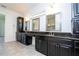 Spacious bathroom featuring dual sinks, granite counters, black cabinets, and large mirrors at 10209 Henbury St, Orlando, FL 32832