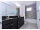 Modern bathroom features a double sink vanity with black cabinets and a gray tiled shower and tub at 10209 Henbury St, Orlando, FL 32832