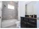 Well-lit bathroom with tiled walls, a black vanity, and a shower-tub combination perfect for relaxation at 10209 Henbury St, Orlando, FL 32832