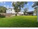 Wide backyard view with a wooden fence, lush green grass, storage shed, and covered patio area at 125 E Grant St, Orlando, FL 32806