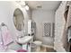 Cozy bathroom with an oval mirror over pedestal sink, toilet, and shower with decorative curtain at 125 E Grant St, Orlando, FL 32806
