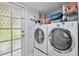 Laundry room with stacked washer and dryer, diamond lattice window, and storage space at 125 E Grant St, Orlando, FL 32806