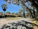 A serene street view featuring a charming light green home nestled under a canopy of trees with dappled sunlight at 171 Church St, Geneva, FL 32732