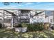 A backyard with an enclosed patio, green grass and trees, with trash bins visible at 17442 Hidden Forest Dr, Clermont, FL 34714
