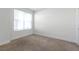 A simple bedroom with neutral carpet, a large window, and freshly painted white walls at 17442 Hidden Forest Dr, Clermont, FL 34714