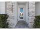 Elegant townhouse entryway featuring stone accents, a glass front door, and manicured bushes at 17442 Hidden Forest Dr, Clermont, FL 34714