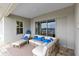 Covered patio featuring stylish outdoor seating, neutral tones, blue pillows, and sliding glass doors at 18405 Mowry Ct, Orlando, FL 32827