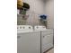 Functional laundry room with white appliances, overhead shelving, and ample space for sorting and folding at 1972 Spring Shower Cir, Kissimmee, FL 34744