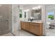 Bathroom featuring double vanity with modern fixtures, large mirror, walk-in shower with glass door, and natural light at 2650 Howard Ave, Oviedo, FL 32765
