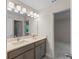 Bright bathroom featuring double sinks, a large mirror, modern lighting, and a doorway leading to a carpeted room at 2650 Howard Ave, Oviedo, FL 32765
