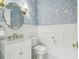 Charming powder room with floral wallpaper, marble countertop, white wainscoting, and brass fixtures at 30215 Island Club Dr, Deer Island, FL 32778