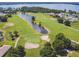 Aerial view of a golf course with ponds, surrounded by lush greenery and water views at 30215 Island Club Dr, Deer Island, FL 32778