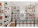 The second story library boasts floor-to-ceiling bookshelves, a chandelier, and ample natural light at 30215 Island Club Dr, Deer Island, FL 32778