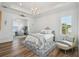 Bright main bedroom featuring a tray ceiling, chandelier, seating area, and shuttered windows at 30215 Island Club Dr, Deer Island, FL 32778