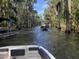 Scenic view of boats navigating a serene swamp, surrounded by lush trees and Spanish moss at 30215 Island Club Dr, Deer Island, FL 32778