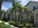 Townhome exterior with well-maintained landscaping, palm trees, and light-colored siding at 5352 Diplomat Ct # 107, Kissimmee, FL 34746