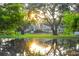 Scenic view of a community pond with mature trees and sunshine at 5352 Diplomat Ct # 107, Kissimmee, FL 34746
