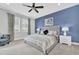 Inviting bedroom with a gray upholstered bed, a blue accent wall, and plenty of natural light at 7419 Marker Ave, Kissimmee, FL 34747