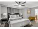 Comfortable bedroom features a fan, grey walls, two side tables, grey drapes and a yellow chair at 8990 Cuban Palm Rd, Kissimmee, FL 34747