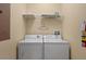 Bright laundry room equipped with a standard washer and dryer set and a shelf for storage at 8990 Cuban Palm Rd, Kissimmee, FL 34747