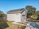 A detached single-car garage with a white exterior stands on a concrete path in the home's backyard at 1112 W Line St, Leesburg, FL 34748