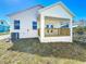Rear exterior view featuring a covered porch with wooden railing and an attached air conditioning unit at 1112 W Line St, Leesburg, FL 34748