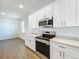 Bright kitchen with white cabinets, stainless steel appliances, light countertop, and light vinyl floors at 1112 W Line St, Leesburg, FL 34748
