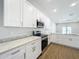 Modern kitchen with white cabinets, stainless steel appliances, and marble countertops at 1112 W Line St, Leesburg, FL 34748