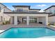 Beautiful backyard with a modern pool, covered patio, and an outdoor kitchen at 15843 Vetta Dr, Bella Collina, FL 34756