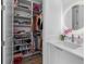 Walk-in closet with custom shelving and storage adjacent to bright modern bathroom at 15843 Vetta Dr, Bella Collina, FL 34756