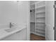 Bathroom with a pristine white vanity and view into the well-organized walk-in closet at 15843 Vetta Dr, Bella Collina, FL 34756