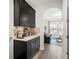 View of the butler's pantry, with custom cabinets and countertops, plus hardwood-style flooring, and an archway to the living room at 16310 Rock Coast Dr, Winter Garden, FL 34787