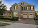 Charming two-story home at dusk with a three-car garage, covered porch, and professionally landscaped yard at 16310 Rock Coast Dr, Winter Garden, FL 34787